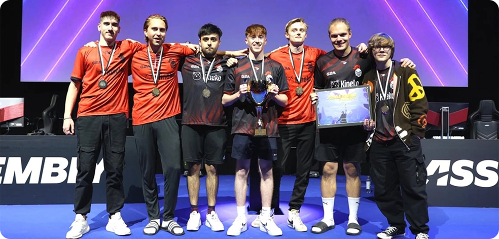 Zeven jonge mannen in identieke rood-zwarte shirts staan samen op een podium, trots hun medailles en een trofee tonend, en stralen een gevoel van triomf en kameraadschap uit