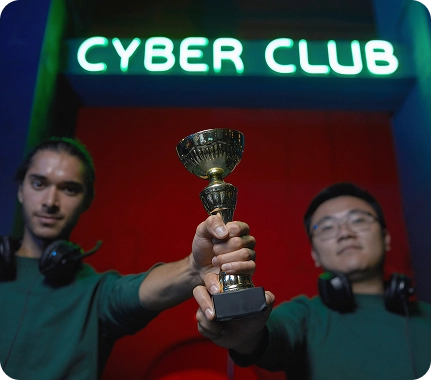 Twee esports-spelers met een headset op die samen een kleine trofee vasthouden voor de ingang van een cyberclub, na een overwinning in een gamingwedstrijd in een met neon verlichte gamelocatie